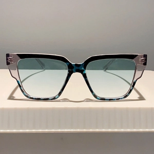 Detail of oversized sunglasses with blue gradient lenses and marbled black blue frames