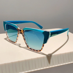 Close-up of geometric two-tone sunglasses with blue and tortoiseshell frames and gradient lenses