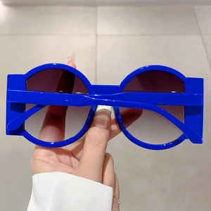 Detail view of bold blue round sunglasses with thick geometric temples and gradient lenses