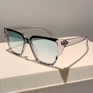 Detail of square oversized sunglasses with purple frame and blue gradient lenses