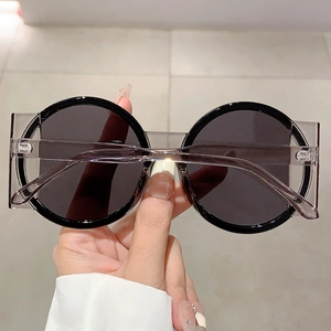Detail of round two-tone sunglasses with black and transparent frames and metal hinges