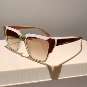 Detail view of square oversized sunglasses with tricolor patchwork frame on a display stand