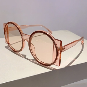 Detail showing the translucent pink geometric frame and round lens of the sunglasses