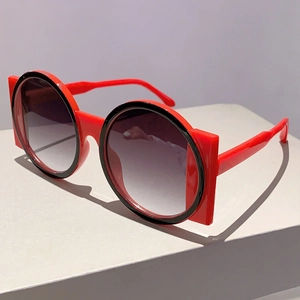 Detail shot of avant-garde red and black two-tone geometric frame sunglasses on a pedestal