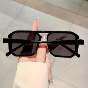 Detailed view of black rectangular sunglasses with thick frames and dark gray lenses
