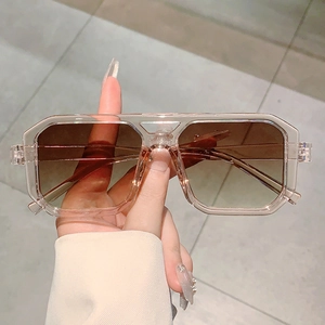 Detail of square sunglasses with transparent champagne frames and gradient brown lenses