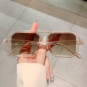 Close-up of pink transparent square sunglasses with gradient brown lenses and dual bridge