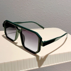 Detail view of dark green square frame sunglasses with double bridge and gradient lenses