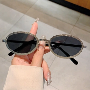 Detailed macro view of the oval sunglasses frame with shimmering crystal embellishments