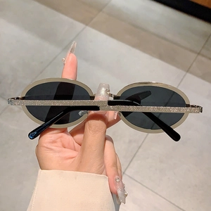 Detail of oval vintage sunglasses featuring textured metallic frame and dark lenses