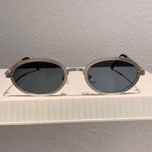 Close-up of vintage oval sunglasses with silver hammered texture metal frames and dark lenses