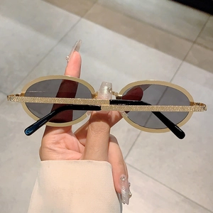 Detail of retro oval gold frame sunglasses showing the glitter textured surface on temples