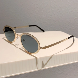 Detail of vintage oval gold metal sunglasses with hammered texture and dark lenses