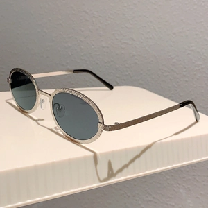 Detail of vintage oval sunglasses featuring a silver hammered metal frame and dark lenses