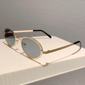 Macro shot of gold oval sunglasses featuring unique hammered metal texture and dark lenses