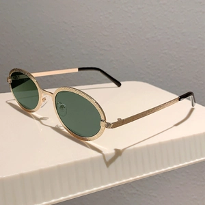 Detail of vintage oval gold metal sunglasses with textured frame and dark green lenses
