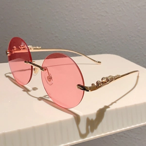 Dettaglio degli occhiali da sole tondi rosa senza montatura con scultura di leopardo oro
