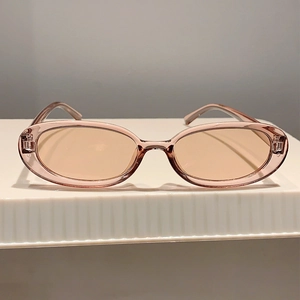 Dettaglio degli occhiali da sole ovali vintage in resina rosa chiaro su supporto bianco
