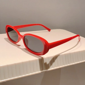 Dettaglio di occhiali da sole ovali vintage con montatura rossa e lenti nere