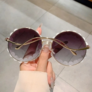 Detailaufnahme einer runden Sonnenbrille mit weißen Wellenkanten und lila Verlaufsgläsern