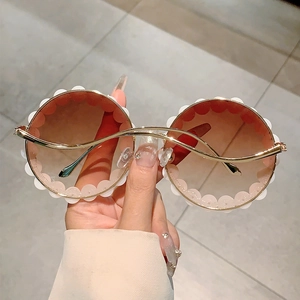Detail einer runden Sonnenbrille mit wellenförmigem Rand und braunem Farbverlauf