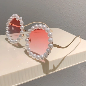 Nahaufnahme der rosa Verlaufs-Sonnenbrille mit perlenbesetztem Rundrahmen auf einem Ständer