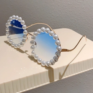 Detailansicht der runden Sonnenbrille mit blauen Verlaufsgläsern und Perlenbesatz am Goldrahmen