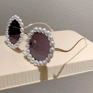 Detailansicht der runden Sonnenbrille mit perlenbesetzten Rahmen und goldenen Bügeln