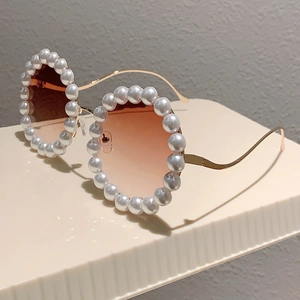 Detail einer runden Sonnenbrille mit perlenbesetzten Rahmen und gewellten Goldbügeln