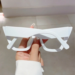 Close-up of white cat-eye fashion glasses showing thick frame and geometric design
