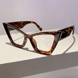 Detail view of tortoiseshell cat-eye glasses frame on a minimalist grey geometric stand