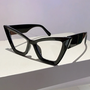 Macro view of thick glossy black cat-eye eyeglass frames on a white platform