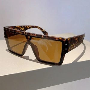 Detail of tortoiseshell square sunglasses with silver stud accents and amber lenses