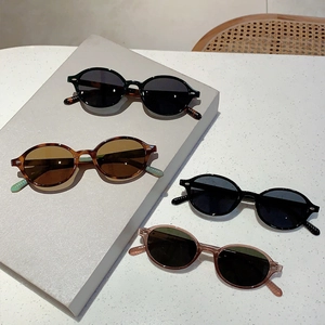 Detail of oval sunglasses in black, tortoiseshell and pink on a textured surface