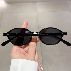 Detail shot of vintage black oval sunglasses featuring silver metal studs on frame