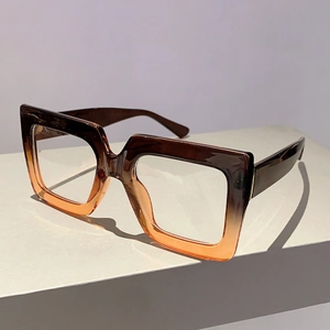 Detail view of square frame glasses with brown to orange gradient color on geometric stand