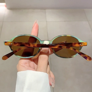 Detail of oval sunglasses with translucent green frame and tortoiseshell temples