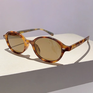Detailed close-up of oval tortoiseshell sunglasses with brown lenses and silver rivets