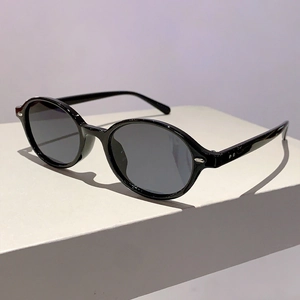 Detail view of oval black sunglasses with silver metal accents on the temple hinge
