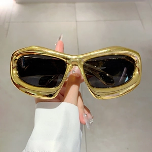 Macro shot of Y2K liquid metal gold frame sunglasses with oversized dark lenses