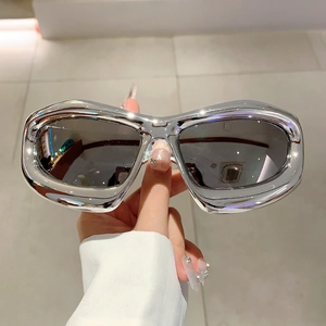 Macro shot of futuristic silver Y2K shield sunglasses with high-gloss metallic finish