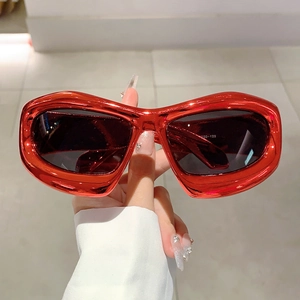 Close-up of metallic red Y2K oversized sunglasses with glossy frame and dark lenses