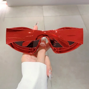 Detail of red metallic heart-shaped Y2K sunglasses with futuristic glossy finish