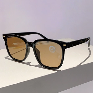 Details einer quadratischen Oversize-Sonnenbrille mit schwarzem Rahmen und bernsteinfarbenen Gläsern