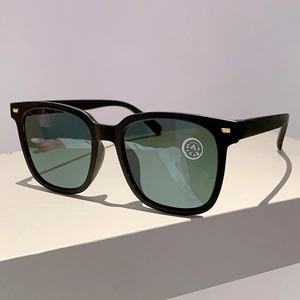 Detail einer quadratischen Kristallglas-Sonnenbrille mit grünen Gläsern und Goldakzenten