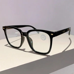 Detail der quadratischen schwarzen Sonnenbrille mit Kristallgläsern und Goldakzenten