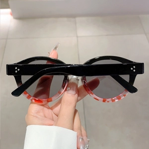 Detail of round sunglasses with black and tortoiseshell frames and metal rivets