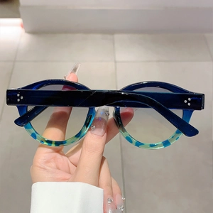 Detail of round tortoiseshell sunglasses with blue acetate frames and rivet accents