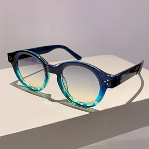 Detail of vintage round sunglasses showing blue-green gradient frame and metal rivets