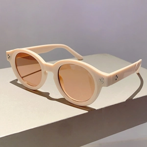 Detailed close-up of retro round beige sunglasses with tea lenses and silver rivets